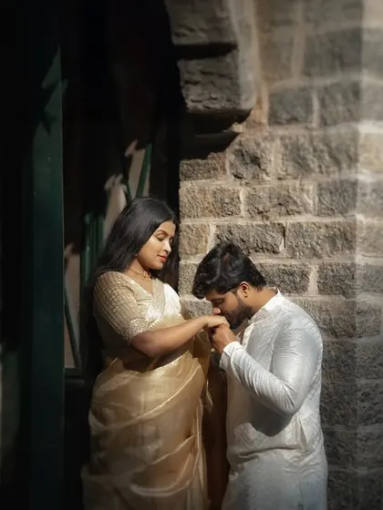 A chivalrous kiss on the hand, framed by the archway of a stone building. The warm, directional light adds a touch of old-world romance to this pre-wedding portrait.