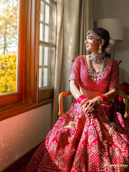 A beautiful bridal portrait, with the bride seated by a window, bathed in soft, natural light that highlights her features and elegant attire.