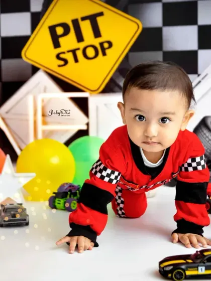 On your marks, get set, go. This little guy is crawling right into his first birthday celebration, surrounded by checkered flags and toy cars.