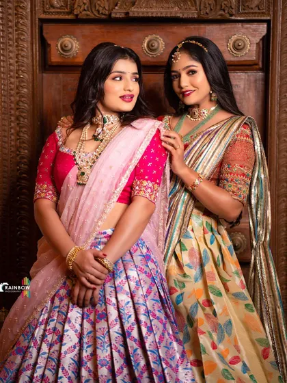 A lovely shot of two models in contrasting silk half sarees, one in pink and blue, the other in a multi-color print.