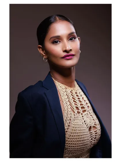 A powerful and confident portrait of a model in a blazer and crochet top. The strong lighting and direct gaze create a look of modern professionalism.