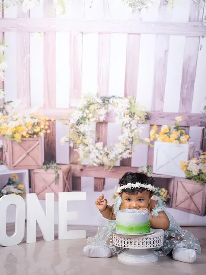 A close-up of the birthday girl enjoying her cake. The rustic garden theme with white and yellow flowers provides a beautiful, natural-feeling backdrop for this sweet moment.