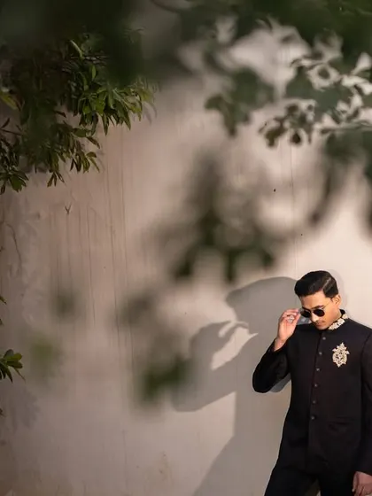 A stylish portrait of the groom in a classic bandhgala, adjusting his sunglasses with a cool demeanor.