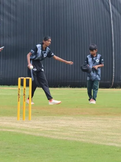 A young female bowler in action during a mixed-gender youth match.