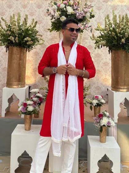 Posing against a backdrop of beautiful floral arrangements. The vibrant red of my kurta adds a pop of color to the scene.