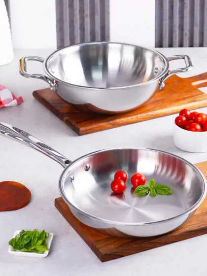 A clean, bright shot of Omichef's stainless steel cookware set. The simple styling with fresh ingredients like tomatoes and basil suggests a fresh cooking experience.