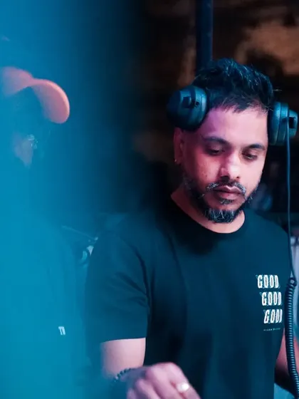 In the zone, focused on the mix. The blue lighting sets a cool, intense mood as I blend techno and deep house tracks to build the energy on the dancefloor.