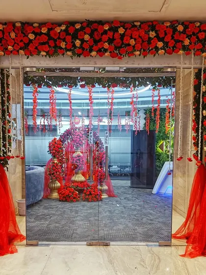 An opulent entrance decorated entirely with red and peach roses. The sheer red fabric adds a touch of softness to this bold and romantic floral statement.