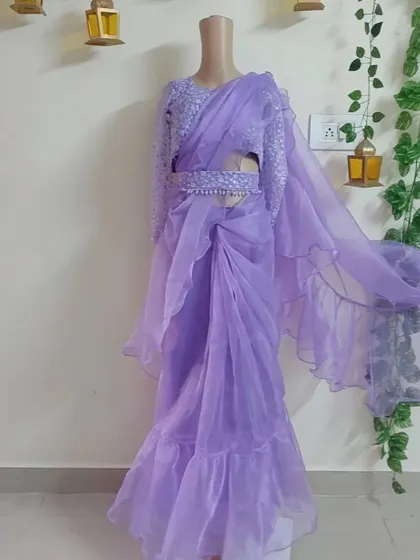 A custom-designed ready-to-wear ruffle saree in a beautiful lavender color. It comes with a fully embroidered blouse and a matching belt for a complete, modern look.