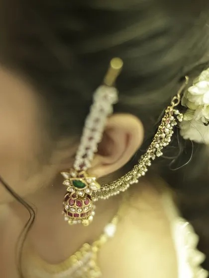 A close-up detail shot of a traditional South Indian bridal earring. This photo highlights the intricate craftsmanship of the jewelry, an essential part of the wedding look.