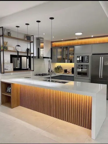 A beautiful kitchen island with a fluted wood base and a waterfall countertop. The open shelving on the side is perfect for cookbooks, and the warm lighting makes it feel so cozy.