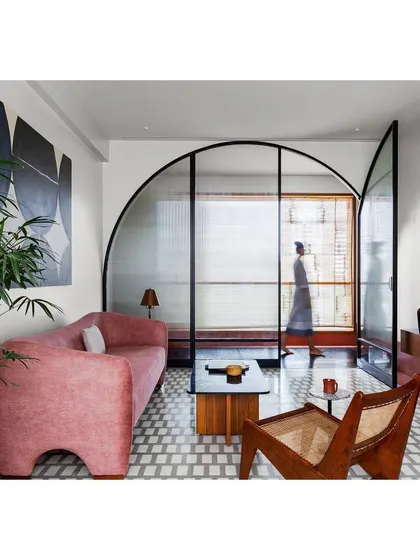 In this lounge, I used a bold color palette and a custom arched glass screen to define the space while maintaining a sense of openness. The design balances modern art with classic materials for a home that feels both exciting and comfortable.