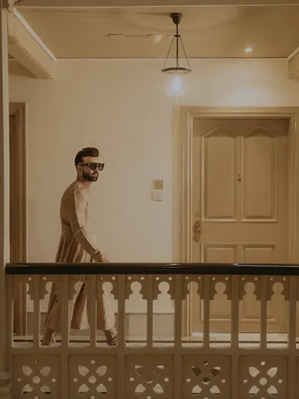 A stylish, cinematic shot of the groom walking through the heritage hotel corridor.