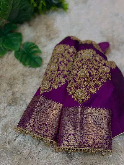 A close-up of the sleeves of the purple blouse, showing the rich zari fabric and detailed gold embroidery.