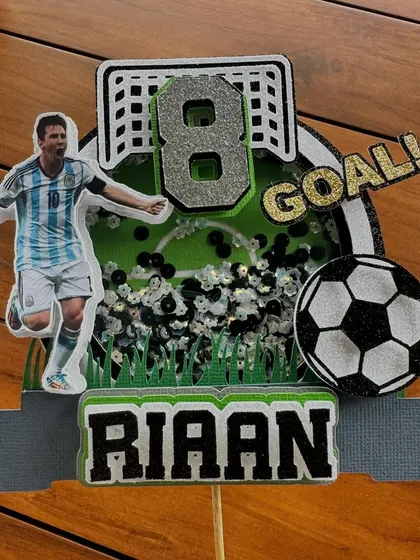 For the Messi fans, this shaker topper captures the excitement of a goal. The layered design and glitter details make it a standout piece for any soccer-themed party.