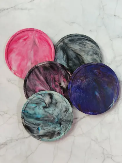 A collection of our lipped coasters, showcasing the variety of stunning marble patterns we can create. From vibrant pink to deep galaxy blue, there's a color for every aesthetic.
