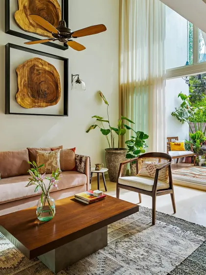 A double-height living room with a large sliding door that opens to a patio. The framed wood slices on the wall are a unique art installation that adds a natural, organic element.