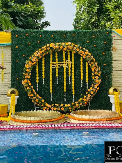 I love creating stunning poolside Haldi setups. For this event, I designed a circular marigold floral backdrop against a lush green wall, complete with traditional brass urlis, making it a perfect blend of modern and classic Haldi decor.