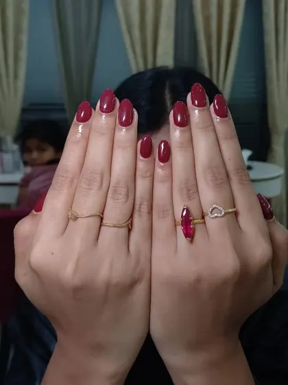 A client showing off her beautiful, glossy dark red manicure. This color is perfect for any occasion.