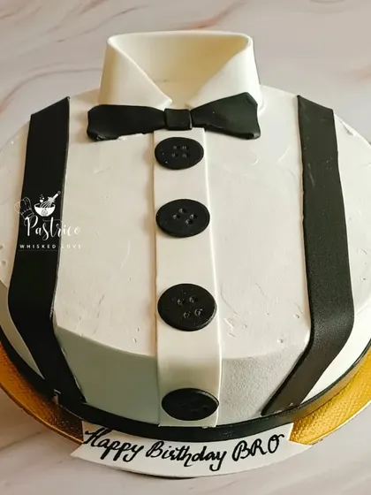 A classic men's birthday cake designed to look like a crisp white shirt with a bow tie and suspenders.
