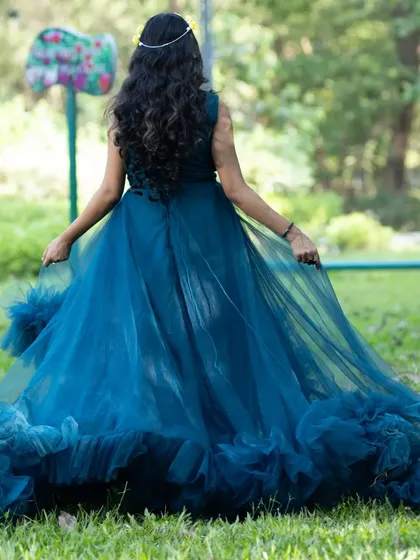 The back view of the turquoise ruffle gown, showing off its beautiful train. It's designed to look like a fairytale dress from every angle.