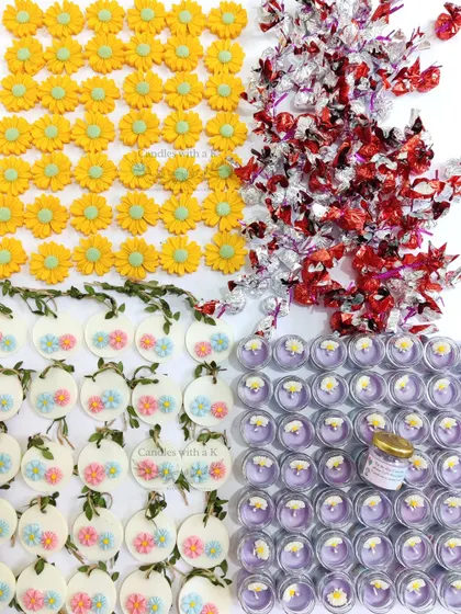 A vibrant display of items for a baby shower gift box: mini jar candles, daisy fridge magnets, and handmade chocolates.