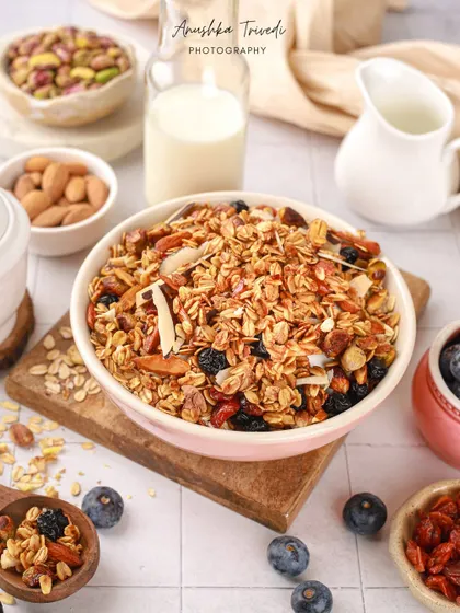 A bowl of crunchy granola, styled with fresh blueberries, nuts, and a bottle of milk for a perfect breakfast scene.