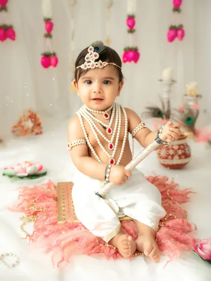 A classic portrait of a baby Krishna holding his flute. The attention to detail in the costume and props makes these themed sessions truly special.