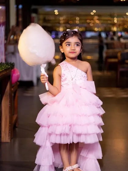 The birthday girl looking chic with a stick of cotton candy, a classic party treat that adds to the fun.