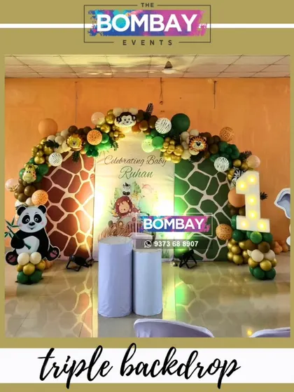 This triple backdrop design adds so much depth to a jungle theme party. The two giraffe-print panels flank a central personalized banner, all framed by a beautiful organic balloon garland.
