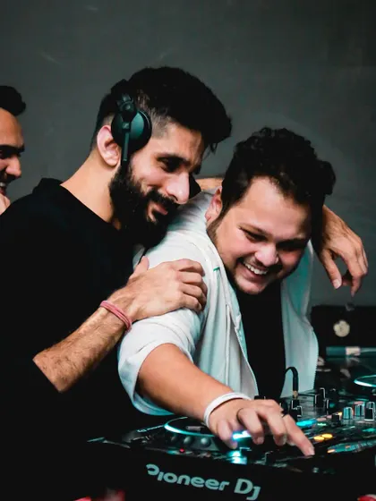 A fun, candid moment sharing a laugh with another DJ behind the decks. It's all about good vibes.