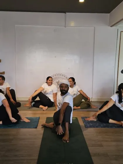 Collective energy and conscious breath. Students practice a seated spinal twist in perfect alignment, demonstrating the harmony of a group class.