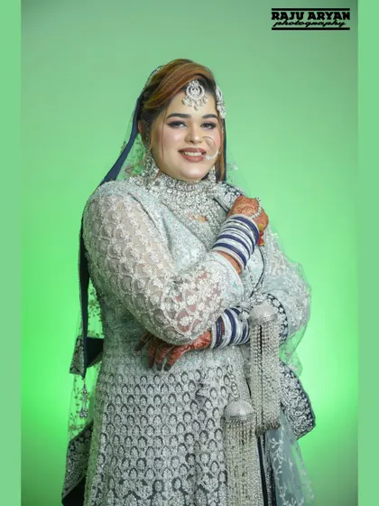 A confident and happy portrait of the bride, showcasing her complete look from the intricate jewelry to the beautiful blue and white bangles.
