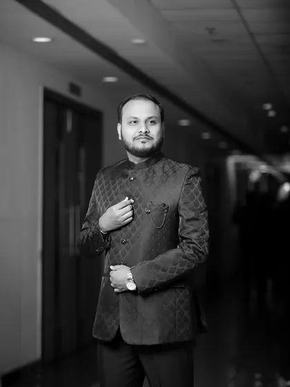 A timeless black and white portrait of the groom in a hallway. The leading lines of the corridor draw the viewer's eye to him, creating a classic and sophisticated image.
