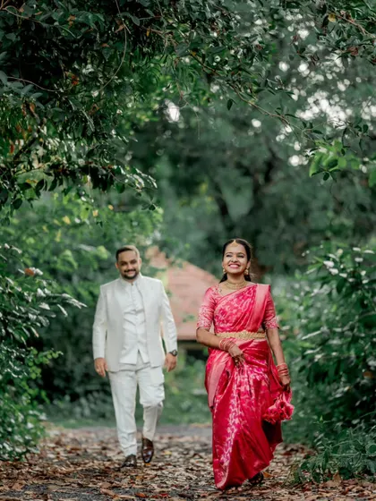 A happy, candid shot of the couple walking and smiling on a path surrounded by nature, capturing the joy of their engagement.