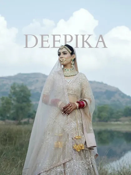 A breathtaking bridal portrait with a mountain and lake backdrop. The bride, named "DEEPIKA," looks regal and serene in her elegant attire.