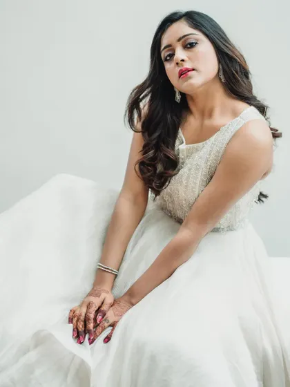 A close-up portrait in a white gown, focusing on expression. The high-key background keeps the attention on the model's face and the detailed texture of the bodice.