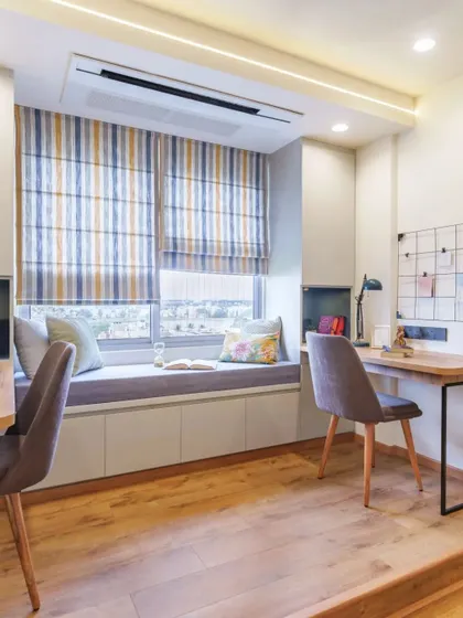 A shared study room with a long bay window seat, providing a comfortable break area between two desk setups.