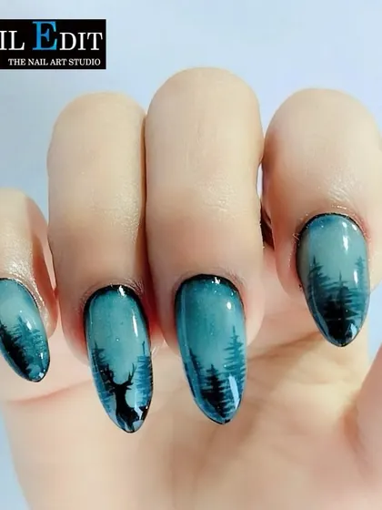 A beautiful example of landscape nail art. This design captures a serene forest silhouette against a dusky teal sky, showcasing our ability to create atmospheric and detailed scenes on a small scale.