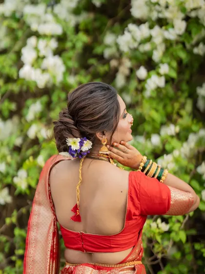 A beautiful shot focusing on the bride's intricate hairstyle, adorned with fresh flowers, and the elegant design of her blouse.