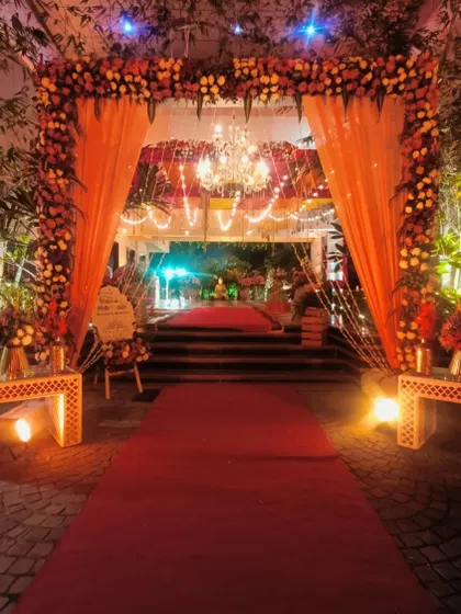 A grand floral entrance for a night event, with a red carpet and a beautiful chandelier creating a luxurious welcome.