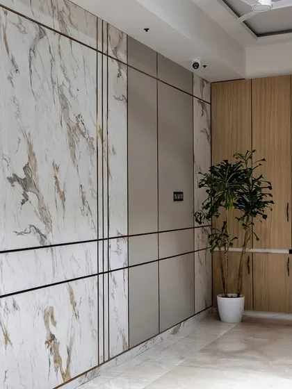 This entryway and living area demonstrate how to create a grand first impression. I used marble-patterned wall panels with metallic inlays and warm wood cabinetry to establish a look of modern luxury from the moment you step inside.