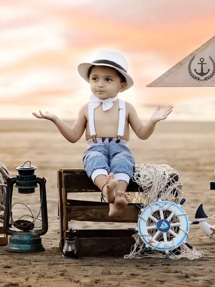 An outdoor sailor-themed shoot on a real beach at sunset. The beautiful light and authentic props like an anchor and lantern create a stunning and adventurous portrait.