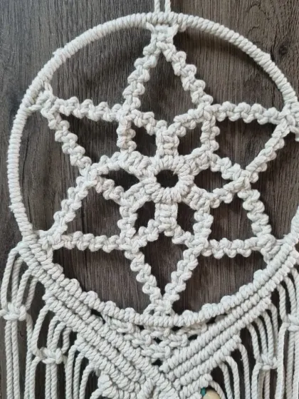 A close up of the star-shaped web at the heart of the dreamcatcher. This pattern is created using a series of carefully placed knots, forming a beautiful geometric design.