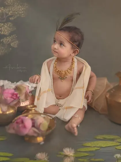 A baby styled as Krishna, sitting by a painted lotus pond. My background as a painter allows me to create these unique, artistic backdrops that transport you into a mythological world.