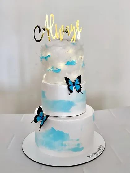 This three-tier 'cloud nine' cake was a dream to make for a Roka ceremony. The top tier is decorated with edible cotton candy to look like a cloud, with delicate blue butterflies adding a touch of magic.