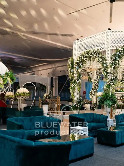The deep teal velvet sofas provide a rich pop of color against the white and floral decor of the reception.