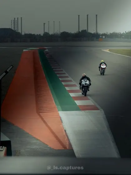 Two superbikes cresting the hill on the back straight of BIC. This atmospheric shot captures the scale and speed of India's premier race track.