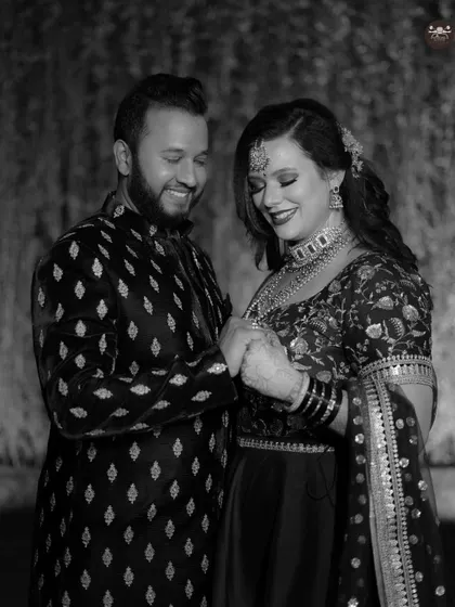 A sweet black and white photo of a couple holding hands and smiling. This candid portrait feels natural and full of warmth, highlighting their bond during the wedding festivities.