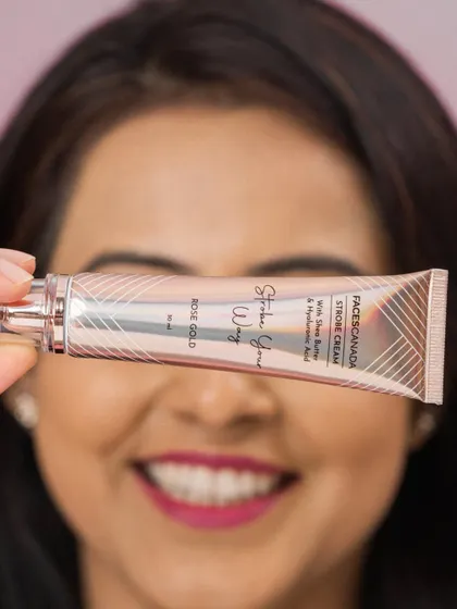 A creative shot where the product tube is held in front of the model's face, drawing the viewer's eye directly to the branding.
